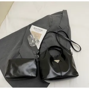 Detail of black glossy leather tote bag set with metal triangle logo and inner pouch