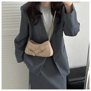 Detailed view of beige baguette bag featuring metal buckle straps on blue blazer
