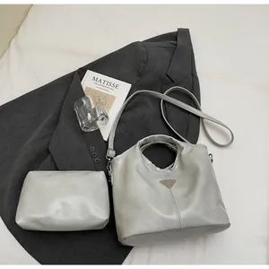 Detail view of light grey PU leather tote bag with silver metal logo and matching pouch