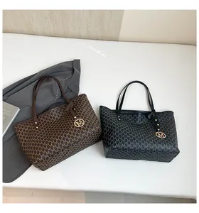 Detailansicht der Monogramm-Tote-Bags in Schwarz und Braun mit edlen Metallanhängern