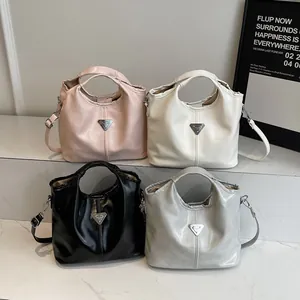 Minimalist faux leather tote bag with triangle logo, shown in four colors on stone steps