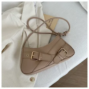 Detailed view of khaki baguette bag with gold buckle straps on a white striped blazer