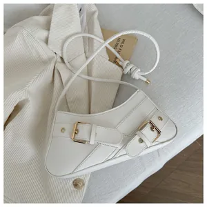 Detail shot of white faux leather bag with golden buckles on corduroy fabric