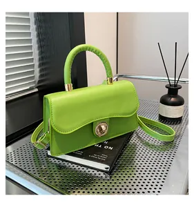 Detail of a bright green crossbody bag featuring a golden circular twist-lock on a metal mesh