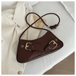 Detail of dark brown faux leather baguette bag featuring vintage gold buckle straps