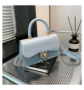 Close-up of light blue handbag with gold metal twist lock and cylindrical top handle