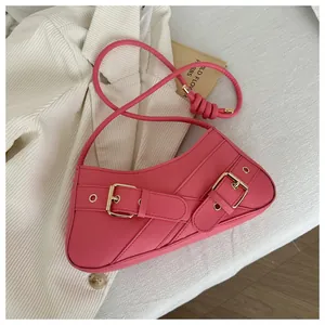 Detail of rose pink baguette bag with asymmetric curves and golden metal buckle accents