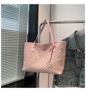 Detail der rosa Monogramm-Tote-Bag mit goldener M-Plakette an einem Metallständer
