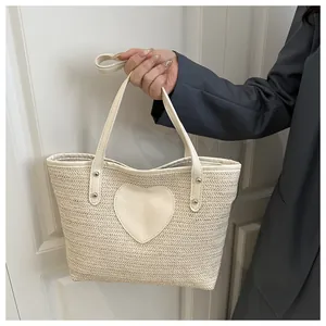 Détail du sac cabas tissé beige avec patch en forme de cœur et rivets métalliques