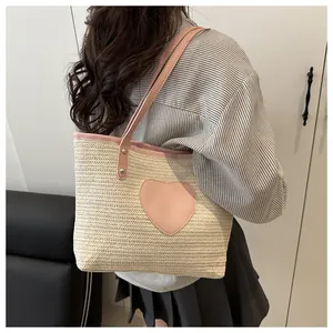 Détail du sac cabas en paille avec écusson cœur rose et poignées en similicuir