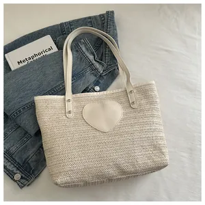 Gros plan détaillé du sac cabas tissé crème avec un empiècement cœur sur toile