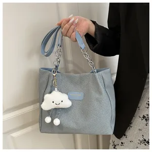 Détail du sac cabas en tweed bleu clair avec bandoulière chaîne et breloque nuage