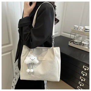 Détail du sac cabas en sergé blanc crème avec étiquette mode et breloque nuage