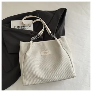 Vue de dessus d'un grand sac cabas crème avec texture sergé et bandoulières en chaîne métallique
