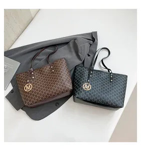 Close-up of monogram pattern tote bag with M-shaped metal charm and smooth leather texture
