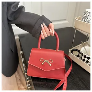 Close-up of a red leather handbag with a golden bow-shaped clasp and top handle