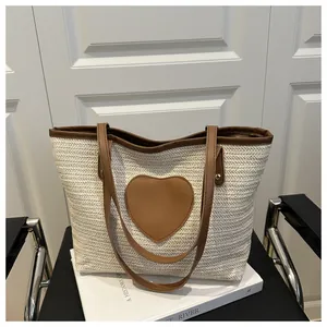 Détail du patch coeur en cuir sur sac cabas tissé crème avec bordure en PU marron