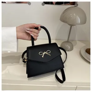 Detailed view of black mini crossbody bag with golden bow hardware and leather handle