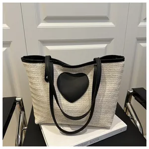 Détail du sac fourre-tout tissé avec anses noires contrastées et écusson en cœur