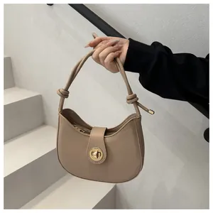 Détail du sac demi-lune beige avec bandoulière à nœud et fermoir doré métallisé