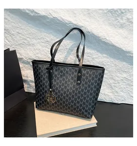Detail of printed pattern texture and golden metal M letter pendant on black tote bag