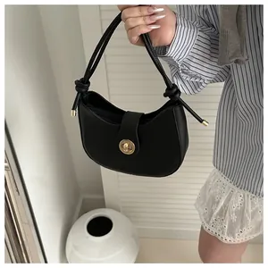 Détail du sac hobo croissant noir avec fermoir en métal doré et bandoulière à nœuds
