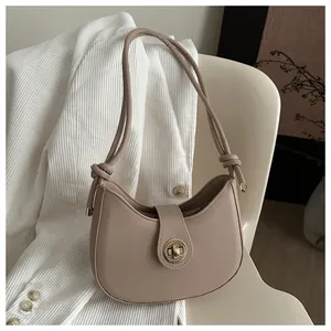 Détail du sac demi-lune beige avec fermoir doré et bandoulière à nœud décoratif
