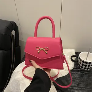 Fuchsia crossbody handbag with golden bow buckle shown in a lifestyle cafe setting