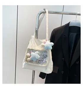 Detail of cream nylon tote bag featuring a transparent PVC front pocket and star pendant
