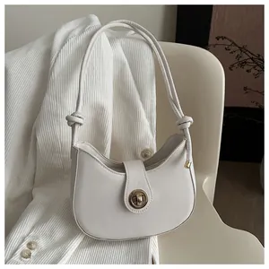 Détail du sac demi-lune minimaliste avec fermoir doré et bandoulière à nœud élégant