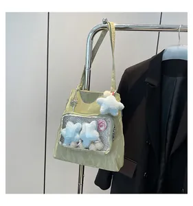 Detail of light green nylon tote with transparent pocket and plush star charms
