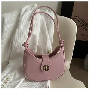Détail d'un sac croissant rose avec fermoir rotatif en métal et bandoulière nouée
