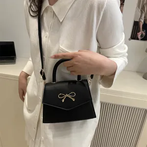 Elegant black mini handbag with gold bow clasp for women featuring a crossbody strap