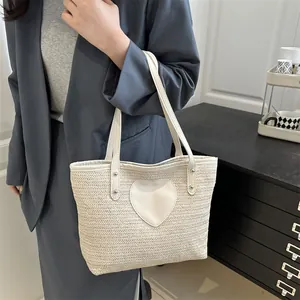 Sac fourre-tout tissé beige chic avec écusson cœur blanc et doubles anses en situation