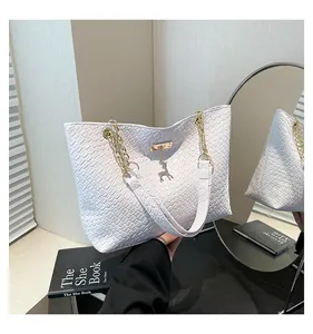 Close-up of white woven embossed leather texture with gold deer pendant and chain strap