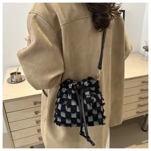 Détail du sac seau à carreaux en tweed avec fermeture à cordon et bandoulière en cuir