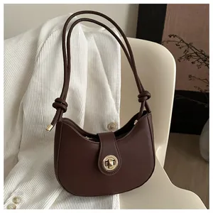 Détail du sac croissant marron foncé avec fermoir doré et bandoulière à nœuds