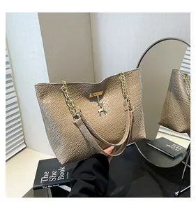 Close-up of woven texture khaki tote bag with golden chain handle and deer charm