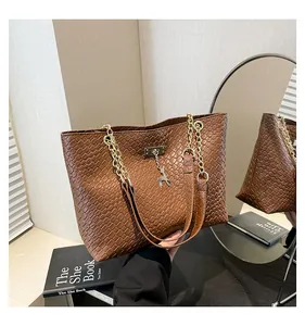 Close-up of brown woven tote bag featuring gold chain strap and deer charm detail
