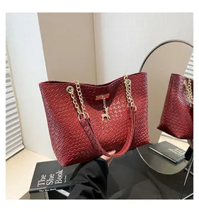 Detail of red woven tote bag featuring gold chain strap and a small deer charm