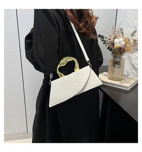 Detalle de bolso blanco de cocodrilo con asa dorada escultural y solapa asimétrica