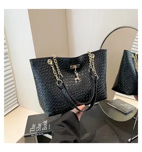 Detail of black woven tote bag featuring gold chain strap and deer pendant ornament
