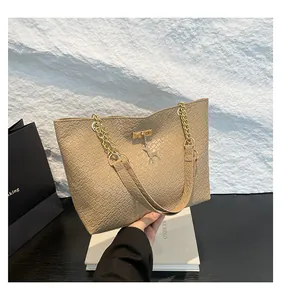 Close-up of beige woven tote bag with gold chain strap and metal deer charm detail