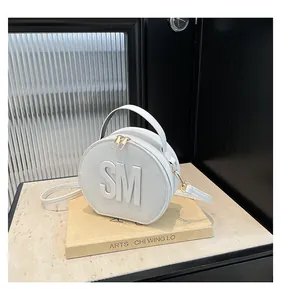 Detail of white round PU leather handbag with gold zippers and SM letter design