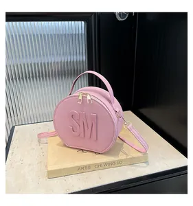Detail of light pink Saffiano leather round bag with embossed SM letters and gold zippers