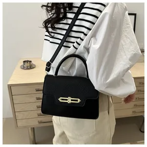 Detailed macro view of the black leather textured flap and gold metal buckle on a handbag