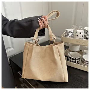 Detailed close-up of beige canvas tote bag showing metal ring handles and woven texture