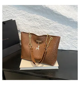 Detail of woven brown tote bag featuring golden deer pendant and chain strap link