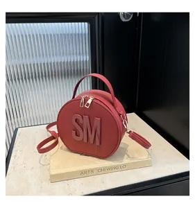 Detail of red circular handbag with embossed SM logo and premium crossgrain texture