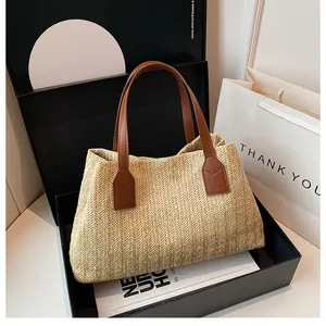 Detail of straw woven tote bag with brown leather handles in a premium gift box setup